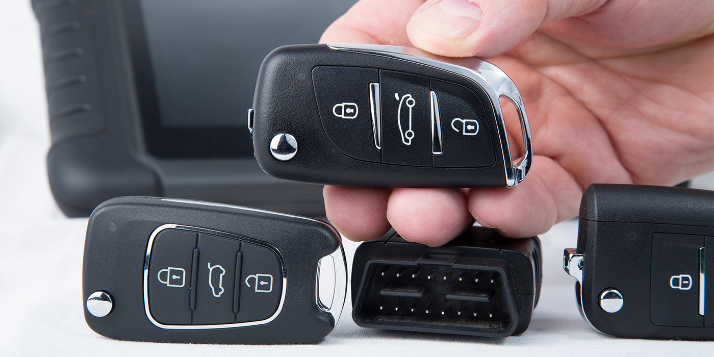 A hand holding a key fob next to a transponder.